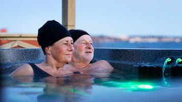 Two people in a hot tub with a cityscape in the background.