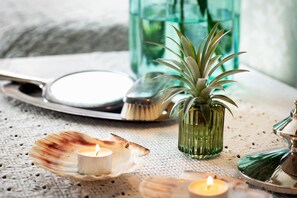 A table with a candle, a shell, a green vase with a plant, and a magnifying glass. - Strandflickornas Havshotell (Lysekil)