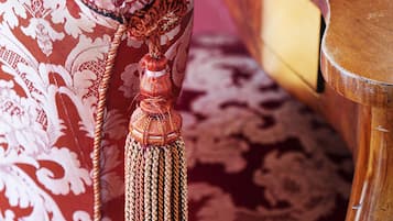 A close-up of a red patterned fabric with a tassel, part of a piece of furniture.