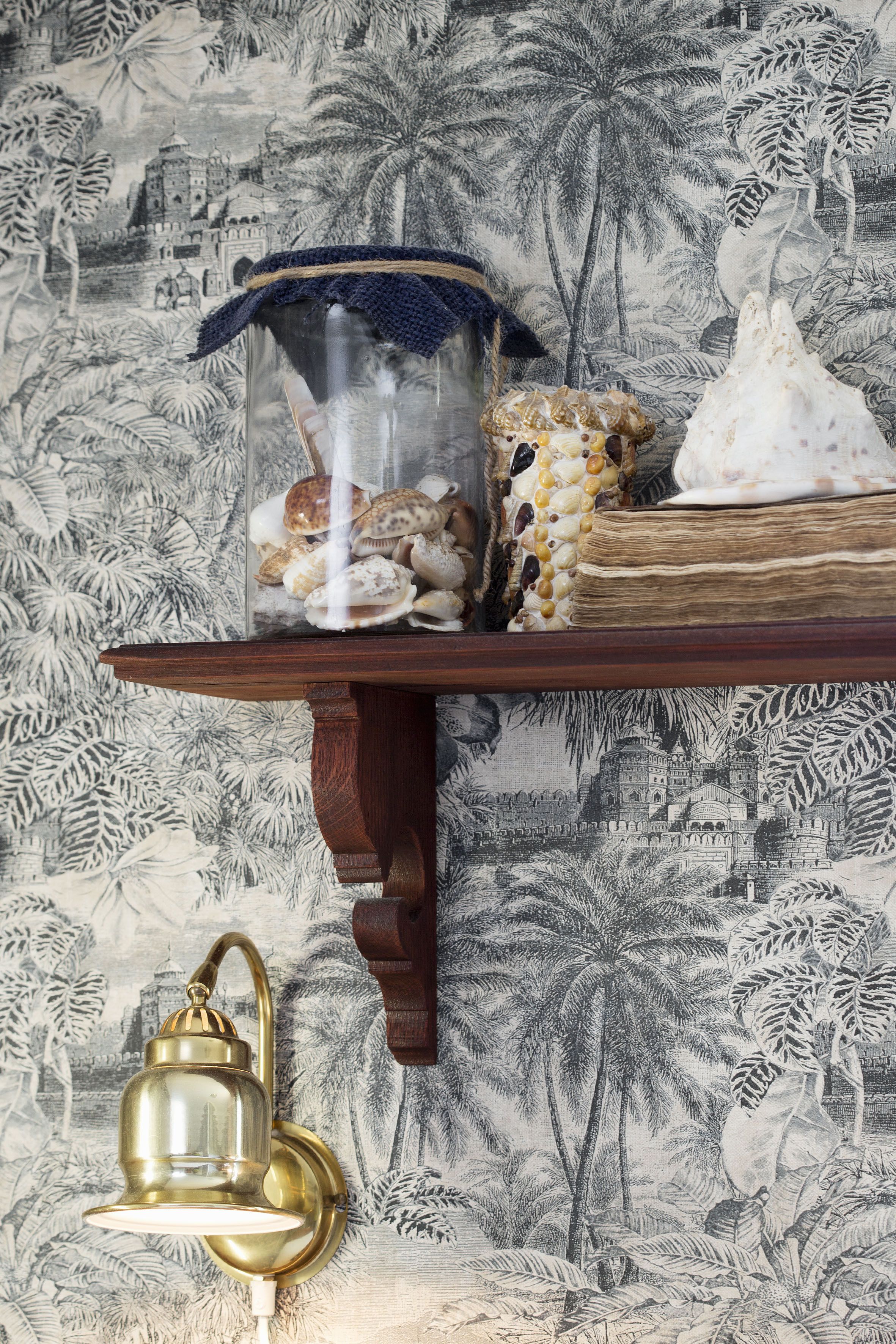 Une étagère ornée d’objets décoratifs, notamment des coquillages, un panier tressé et un livre.