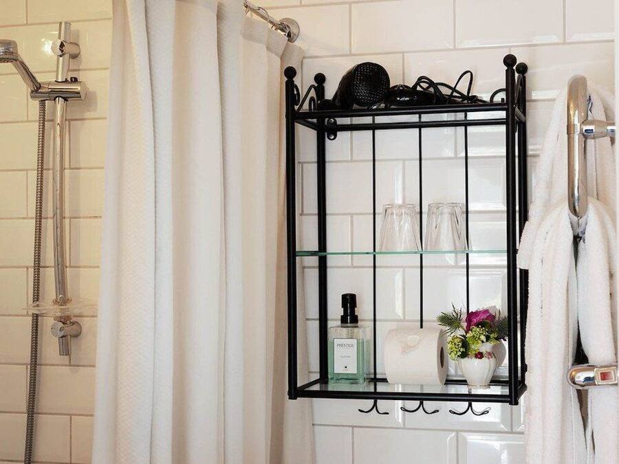 Un baño con repisa de vidrio que contiene artículos de aseo, ducha y toallero.