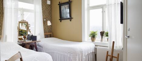 Un dormitorio con dos camas, un tocador, un espejo y una ventana con cortinas.