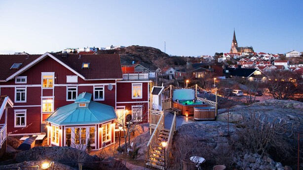 A red building with a blue roof, a wooden deck, and a hot tub. - Strandflickornas Havshotell (Lysekil)
