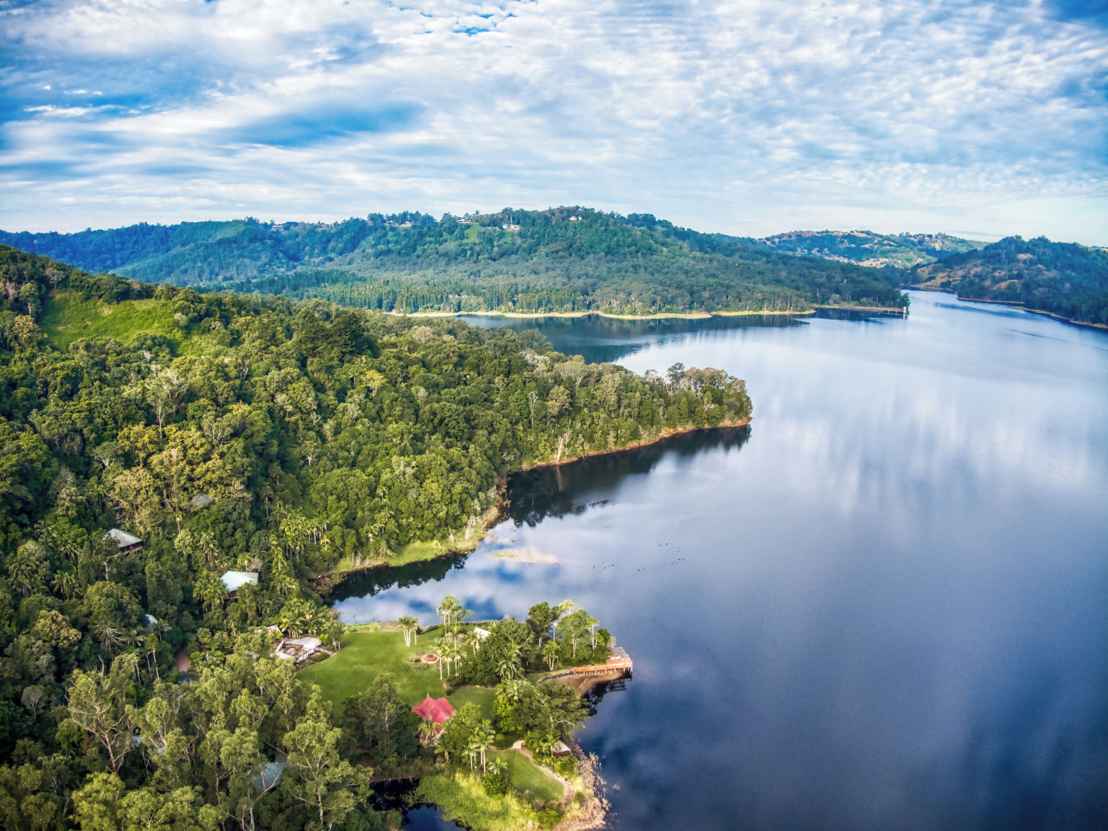 An aerial view of a lake surrounded by dense forest and hills.