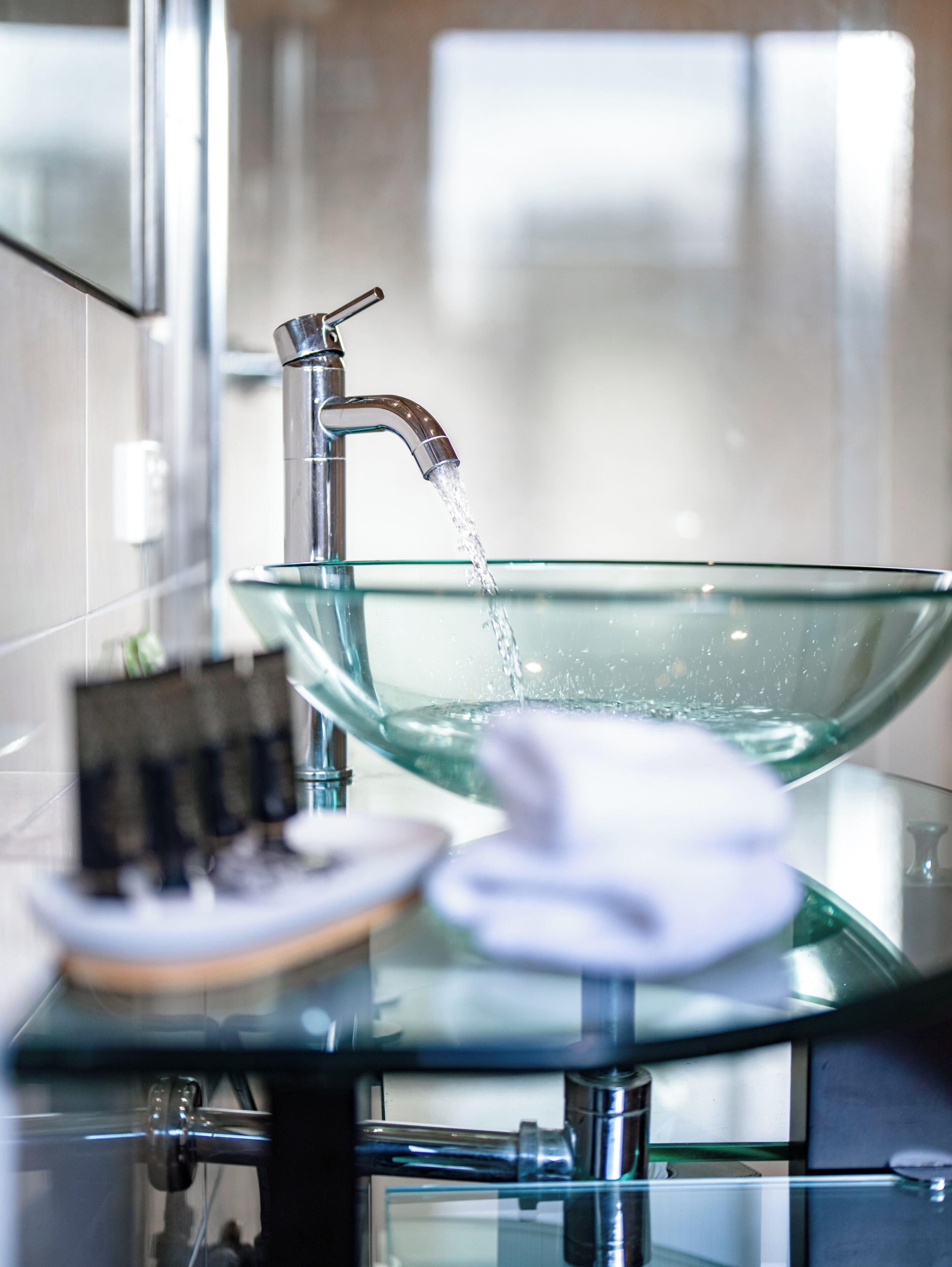 Une salle de bain moderne avec un lavabo en forme de bol en verre, un robinet et un porte-serviettes.