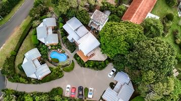 A residential area with multiple houses, a swimming pool, and a parking lot with several cars.