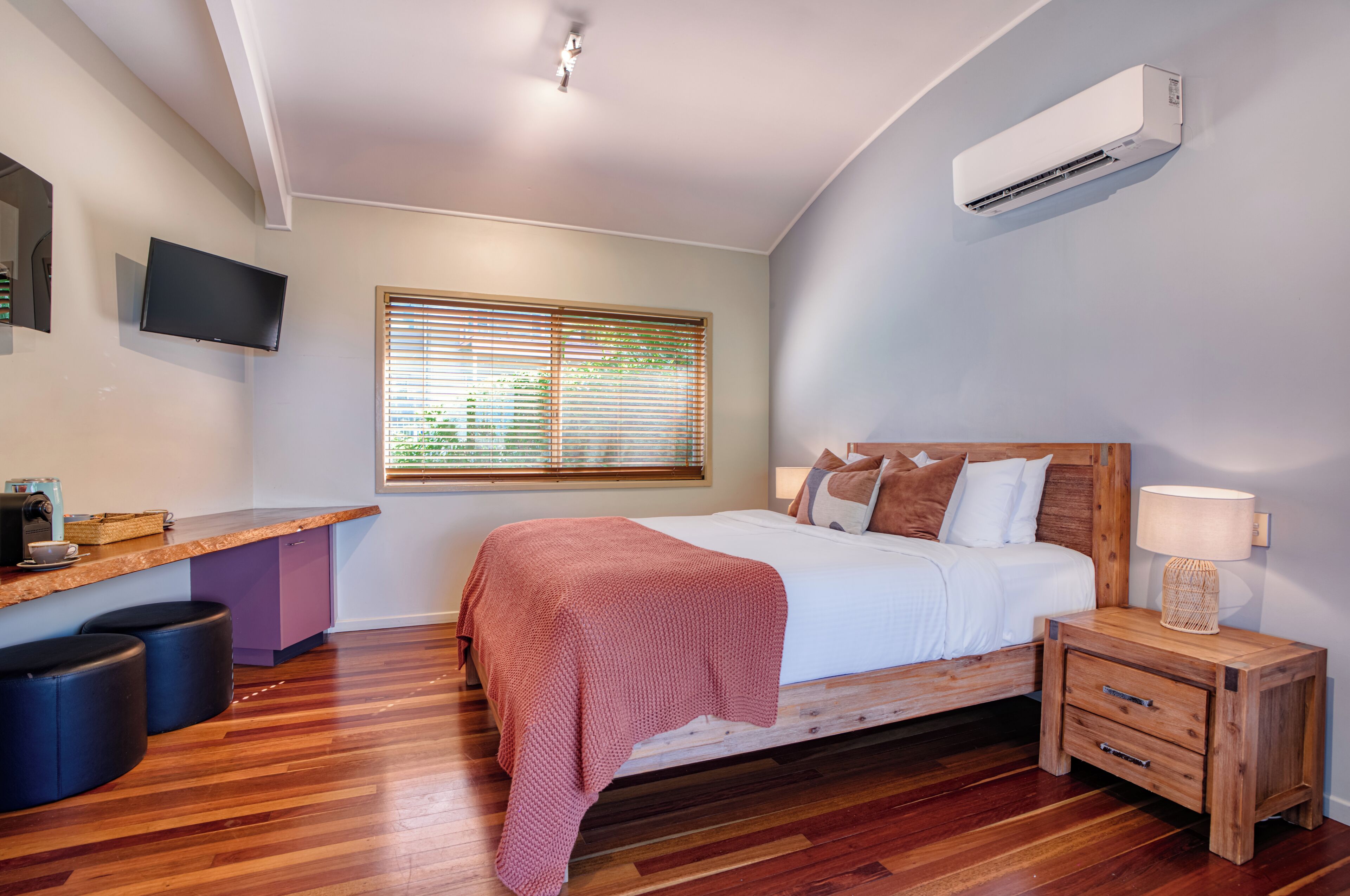 Un dormitorio con cama, mesita de noche, lámpara y equipo de aire acondicionado.