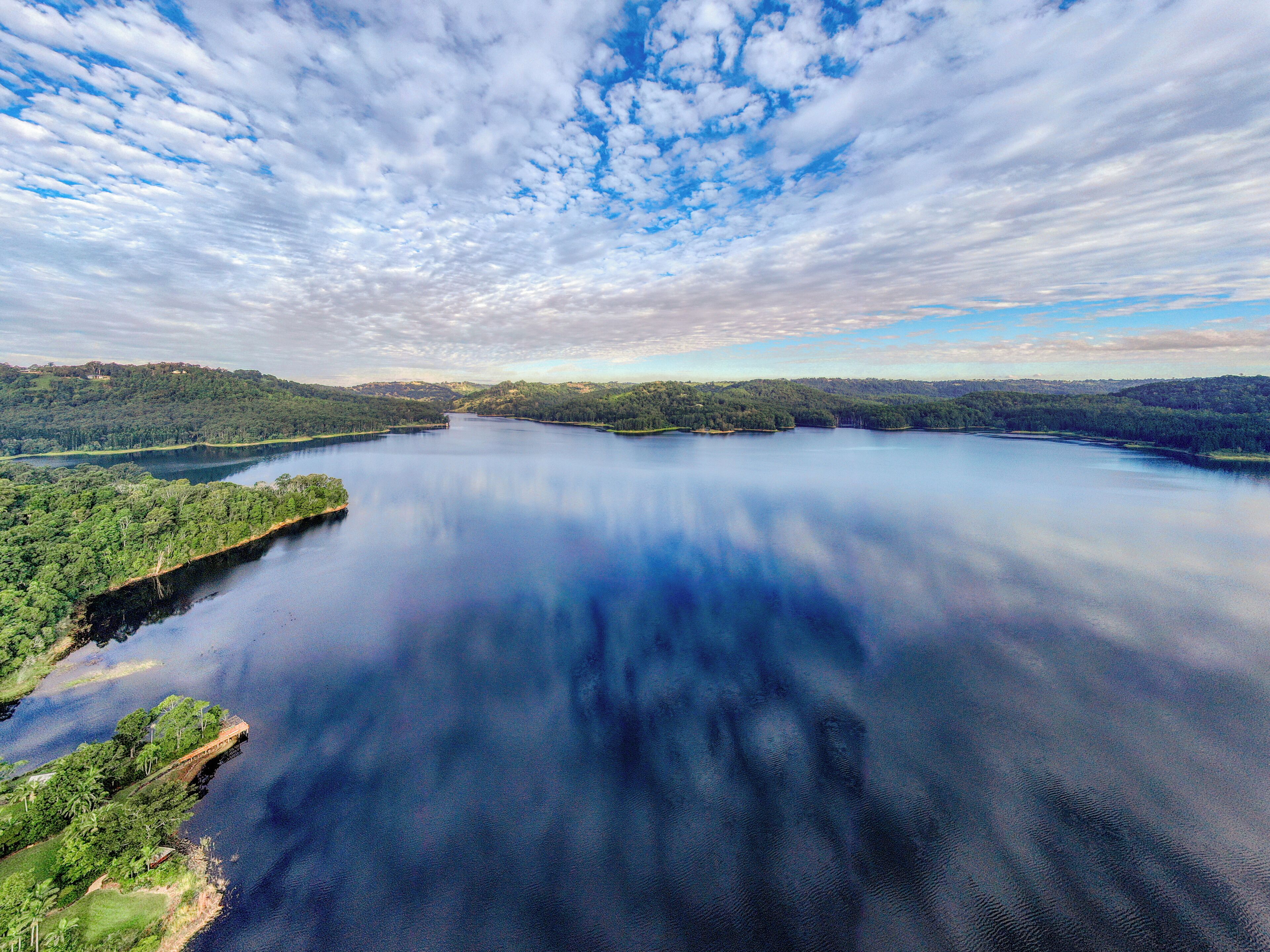 A large body of water surrounded by forested hills.