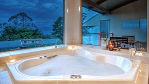 Une salle de bain moderne avec une grande baignoire, un banc et une vue sur l’extérieur.