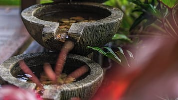 A tiered stone water feature with water flowing through it, surrounded by greenery.