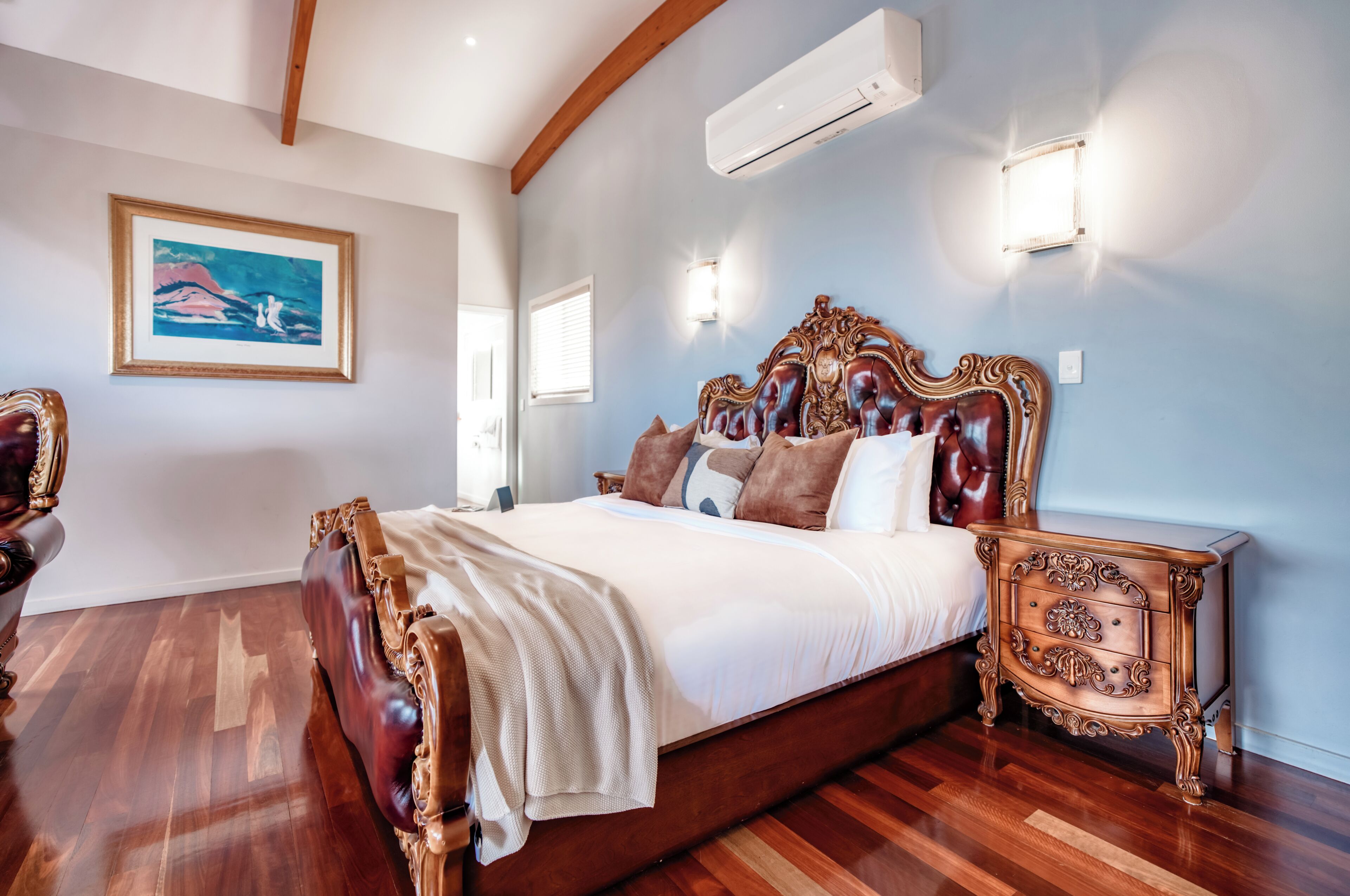 Une chambre avec un grand lit, un plancher en bois et une table de chevet dotée de tiroirs.