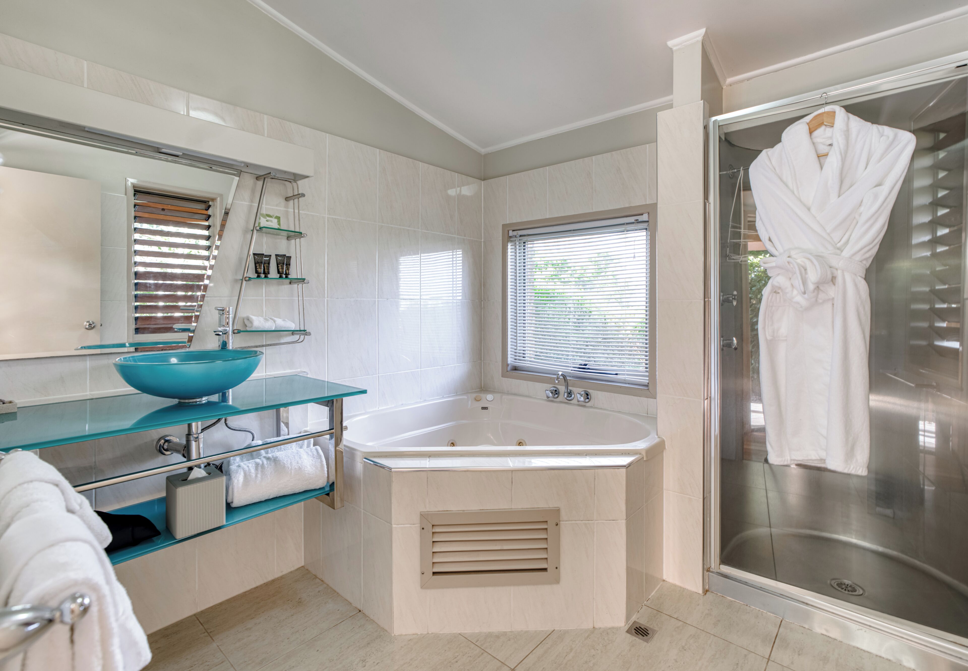 Une salle de bain moderne avec un lavabo en verre, une grande baignoire et une douche à l’italienne.