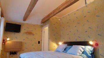 A bedroom with a bed, a television on the wall, and a wooden ceiling beam.