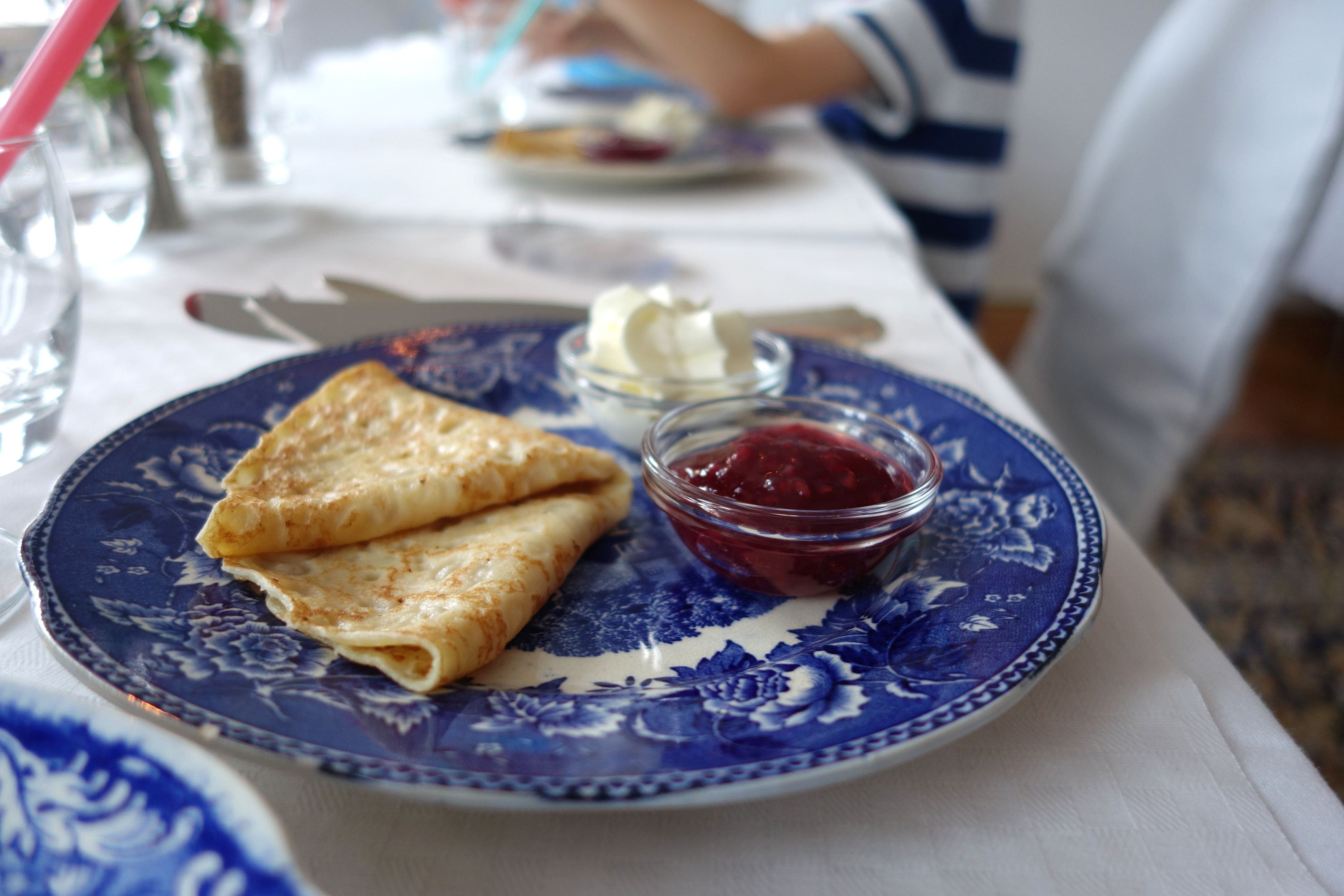 Un plato de crepas y un recipiente pequeño de mermelada.