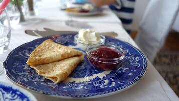 Un plato de crepas y un recipiente pequeño de mermelada.