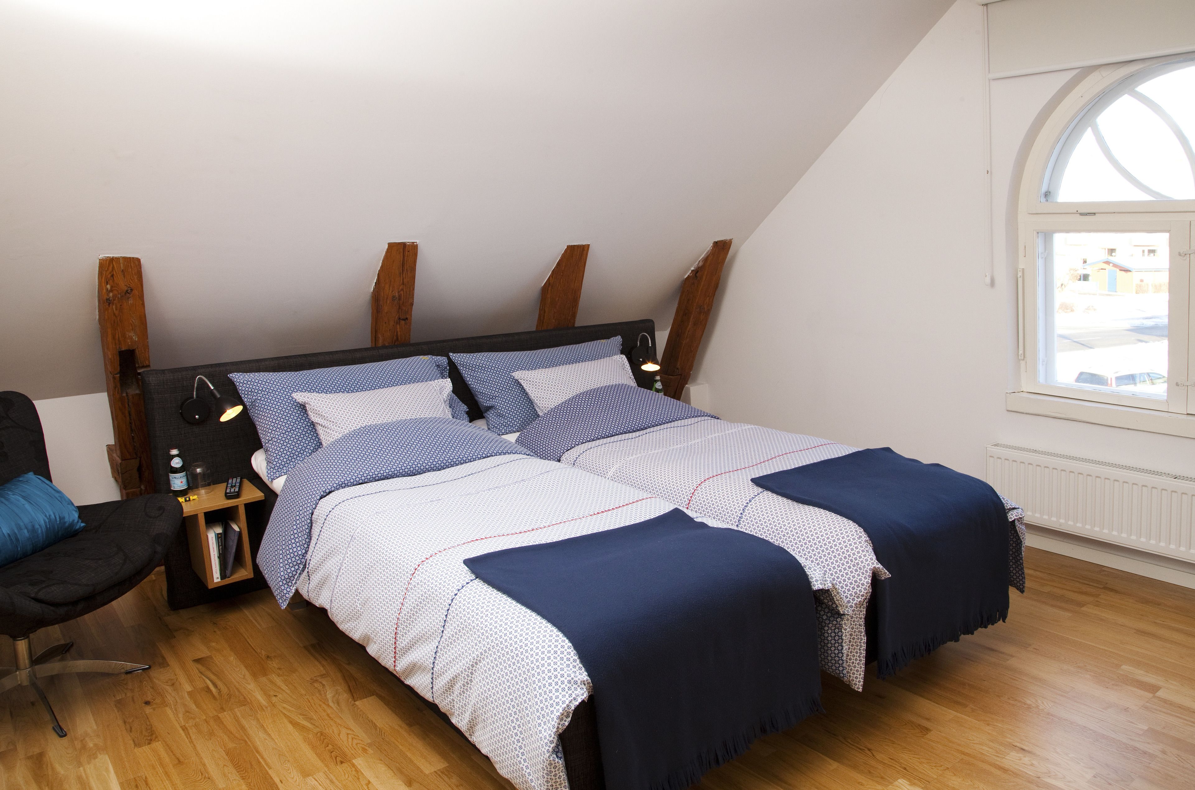Een slaapkamer met een bed, nachtkastjes, een stoel en een raam.