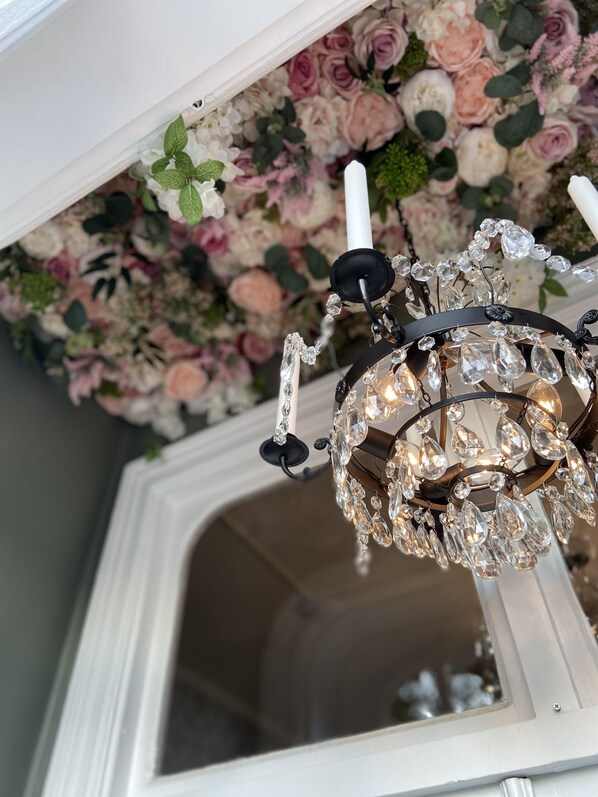 Un candelabro con adornos de cristal y una pared blanca con estampado floral.