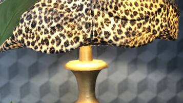 Una lámpara con pantalla de estampado de leopardo, una figurita y una planta.