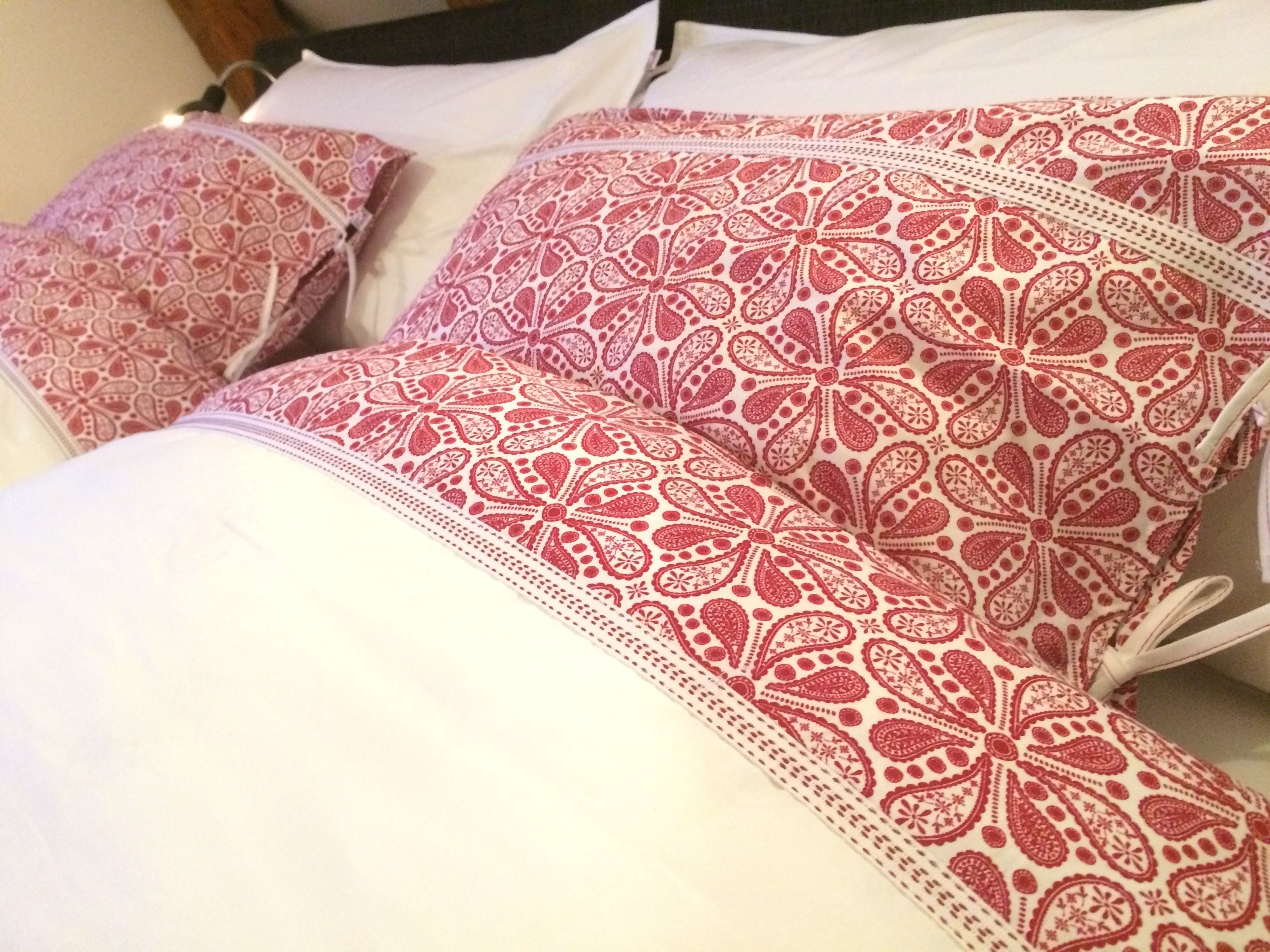 Una cama con muchas almohadas de estampado paisley.