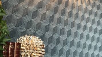 En mönstrad matta med ett geometriskt motiv, en hög med röda böcker och en dekorativ tallkotte.