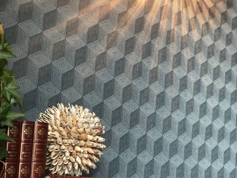 Una alfombra estampada con diseño geométrico, una pila de libros rojos y una piña decorativa.