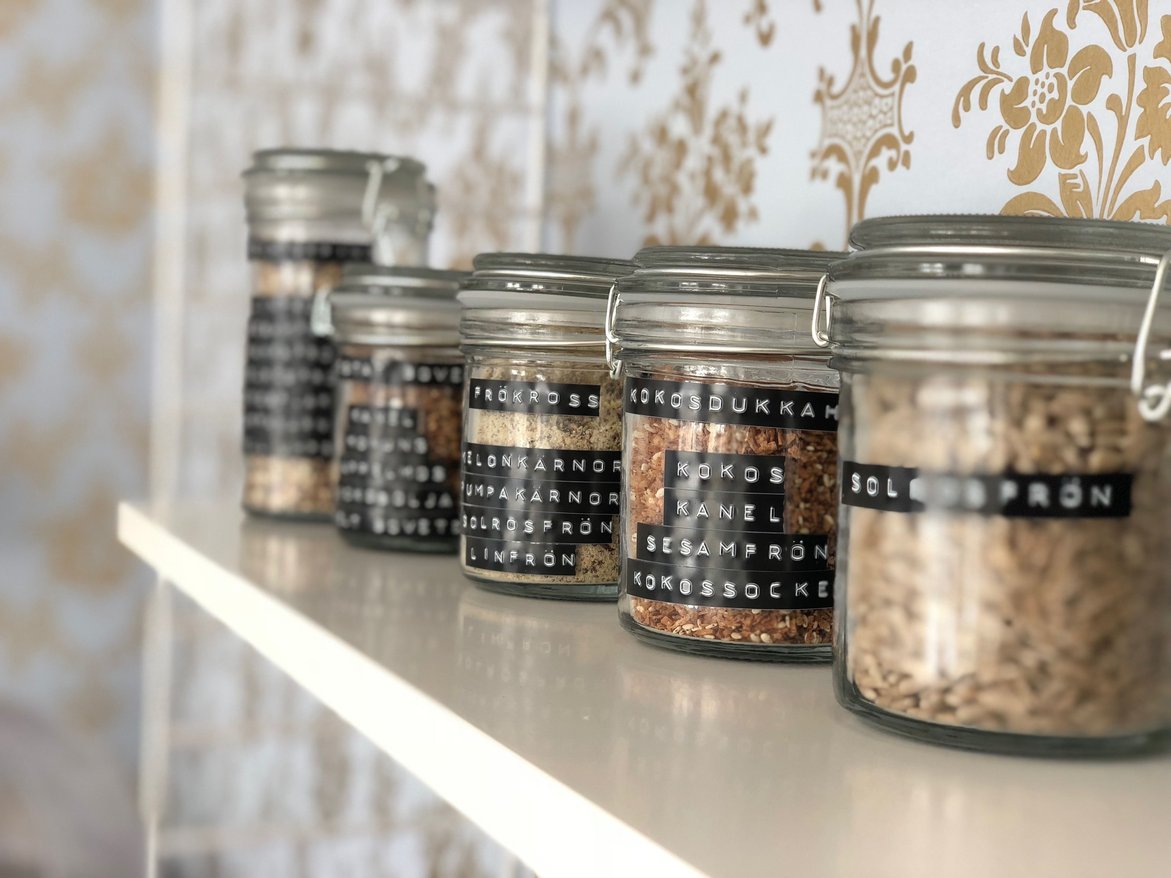 A row of glass jars with labels on a shelf.