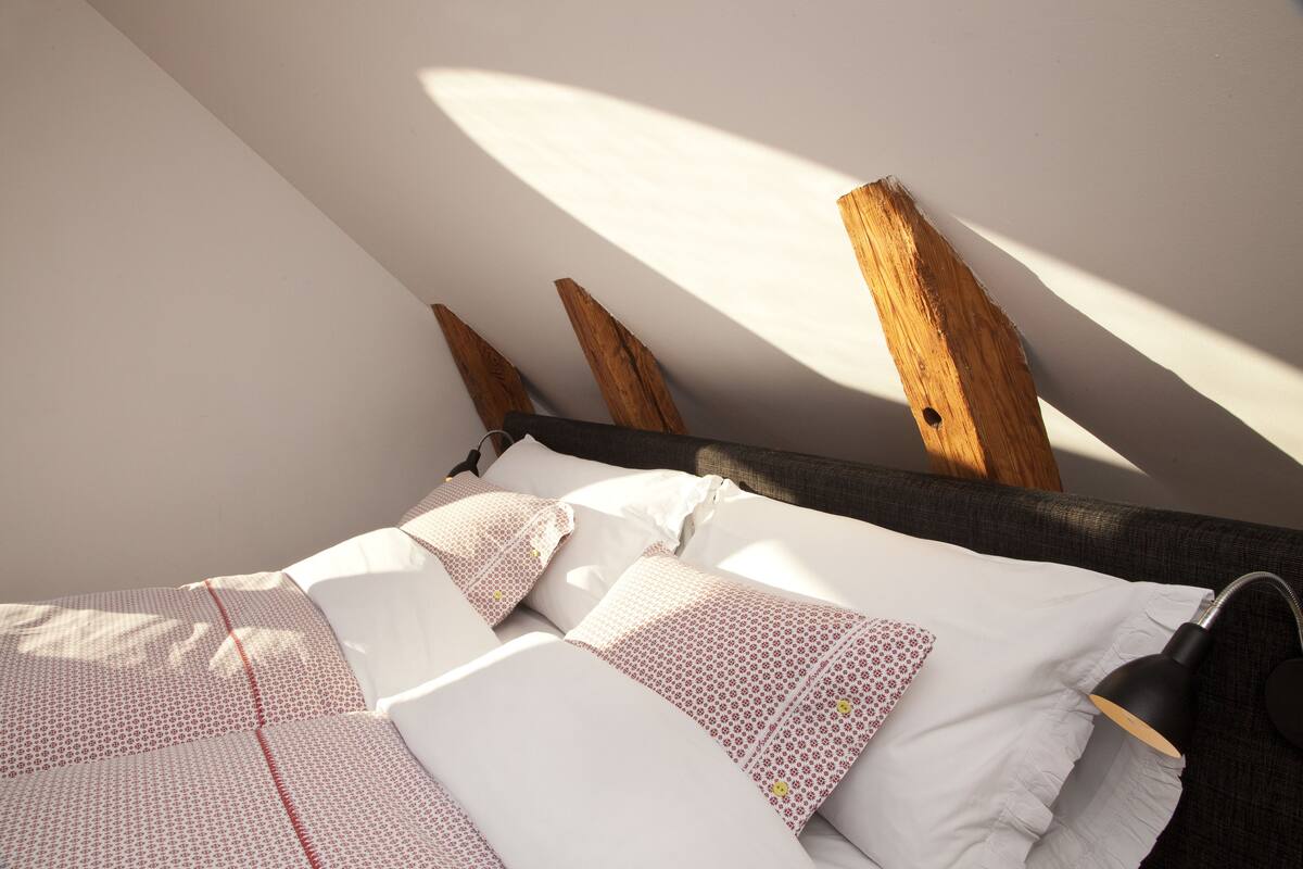 A bedroom with a bed, pillows, and a lamp.