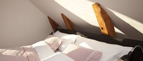 A bedroom with a bed, pillows, and a lamp.
