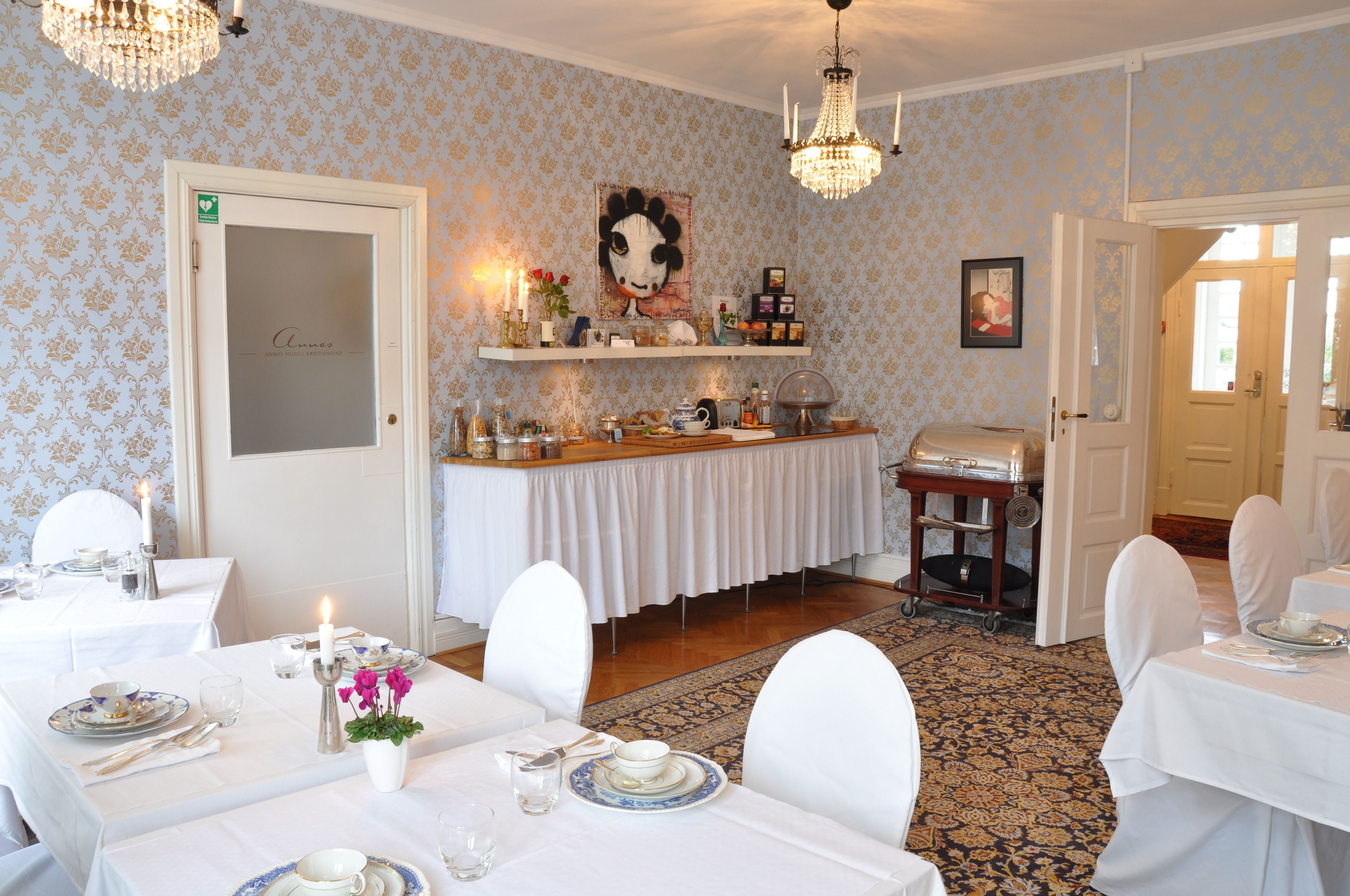 Un comedor con mesas dispuestas para una comida, una estación de buffet y una araña.