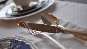 Mesa posta com faca, colher e garfo sobre um pano de mesa branco.