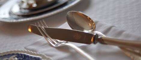 Mesa con un cuchillo, una cuchara y un tenedor sobre un mantel blanco.