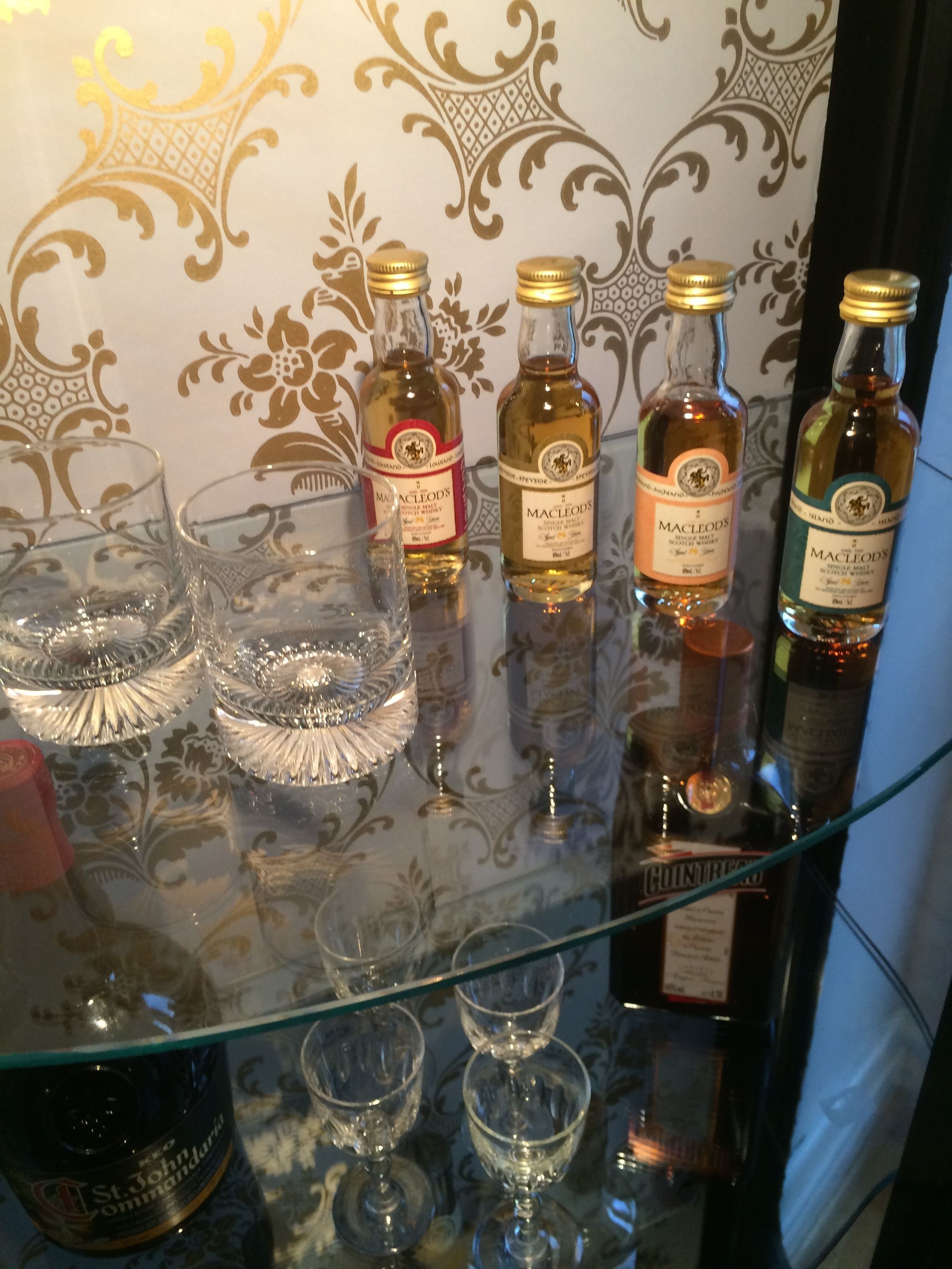Ein Glasregal mit Macleod's Whisky-Flaschen und Gläsern.