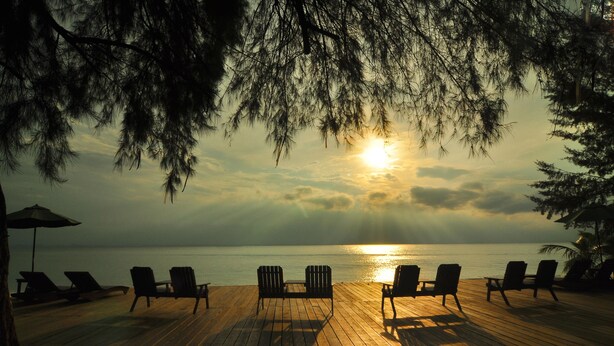 A wooden deck with lounge chairs facing a sunset over the ocean. - Aseania Resort Pulau Besar (Pulau Besar)