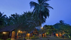 A resort with multiple wooden cabins, surrounded by lush greenery and palm trees, under a twilight sky. - Aseania Resort Pulau Besar (Pulau Besar)