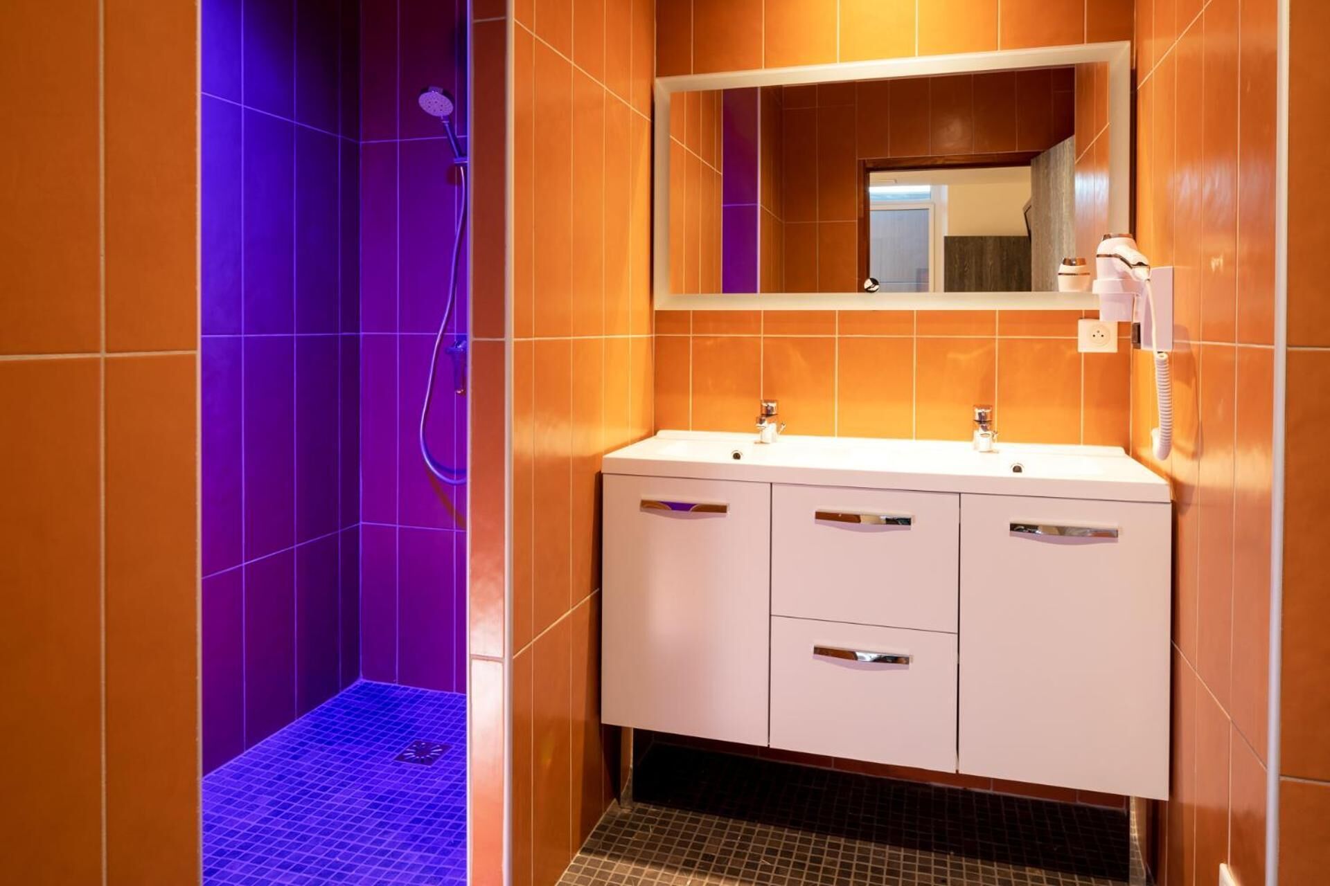 A bathroom with a shower, two sinks, and a mirror.