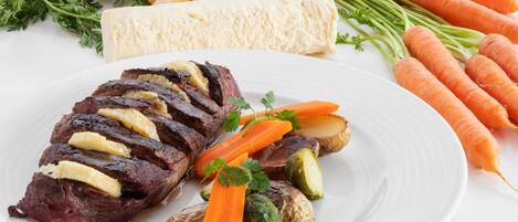 A plate with sliced meat, carrots, and Brussels sprouts.