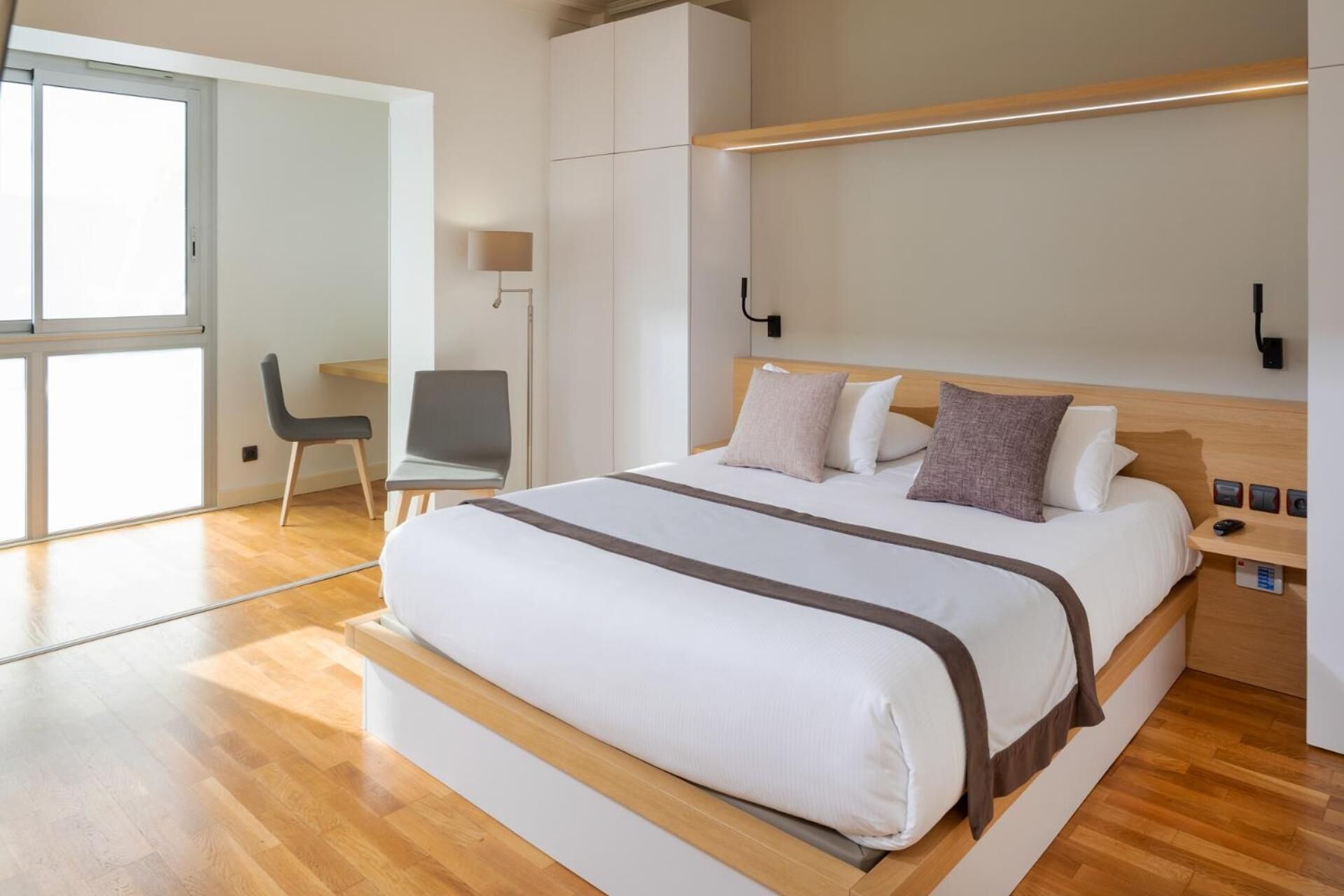 Una habitación de hotel moderna con una cama grande, un escritorio y una silla.
