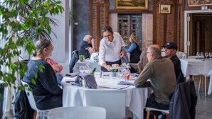 A restaurant with round tables, diners, and a waiter serving food.