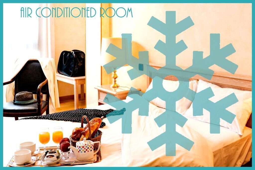 Habitación de hotel con cama, una silla, una mesa con artículos de desayuno y una ventana con cortinas.