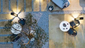 An aerial view of a courtyard with a seating area, a small table, and a tree.