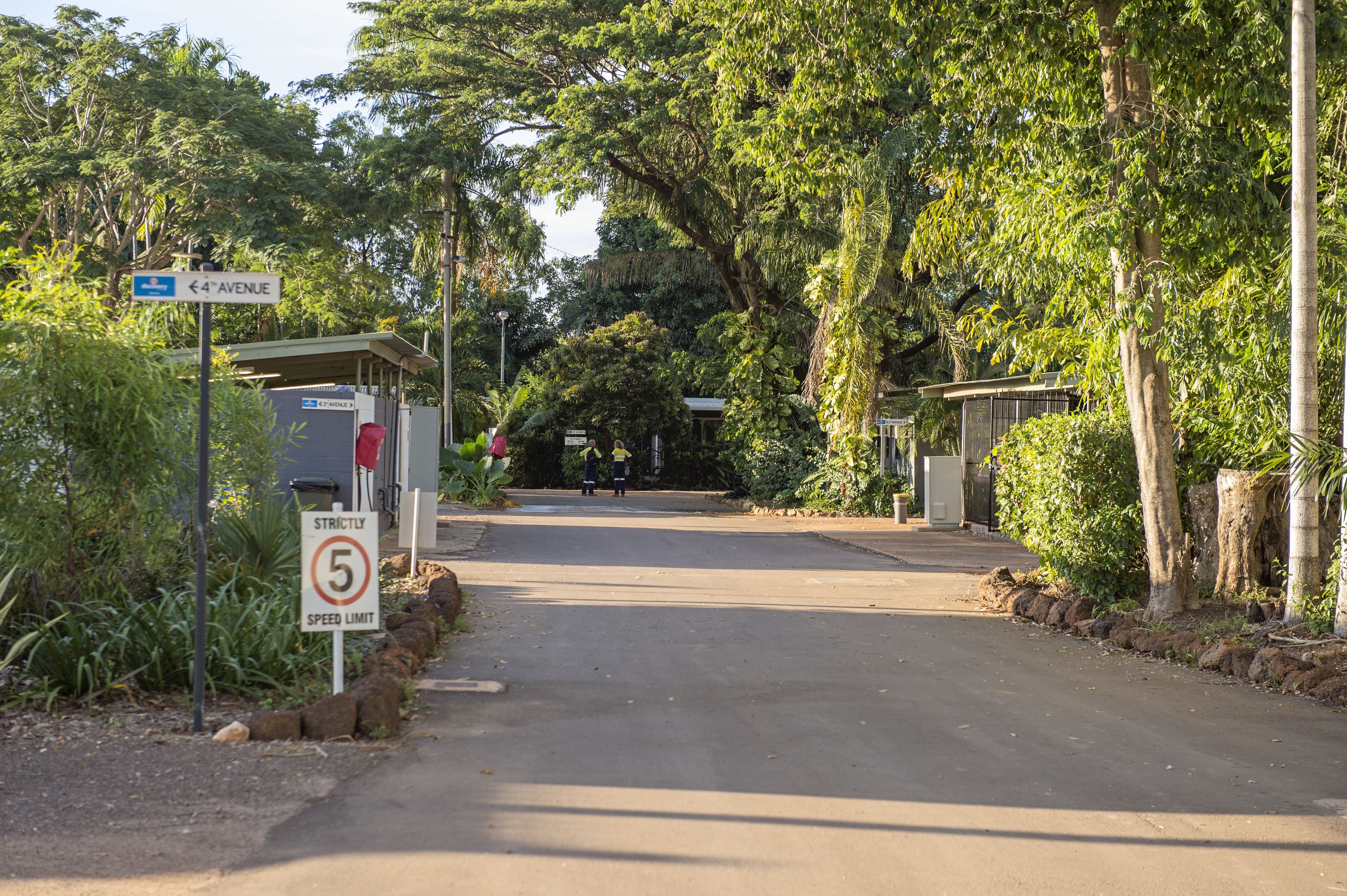 A road leading to a gated entrance with a speed limit sign and a street sign indicating '4th Avenue'.