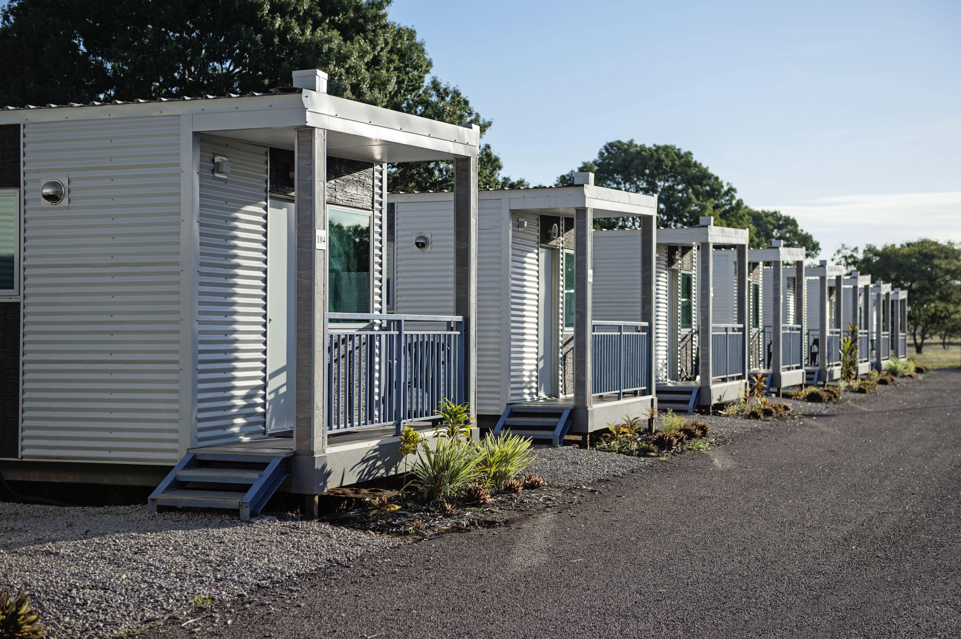 A row of white mobile homes with balconies and steps leading to the entrance.