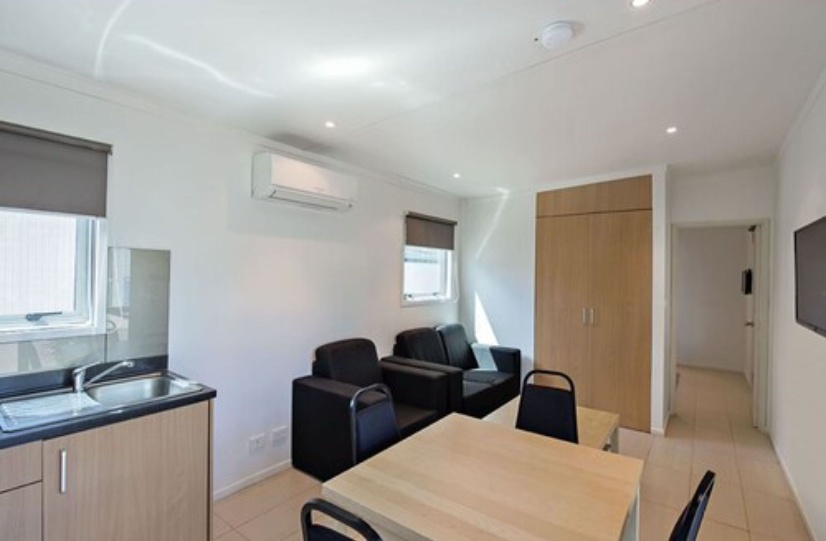 A modern kitchen with a built-in sink, a dining area with a table and chairs, and a small seating area with sofas.