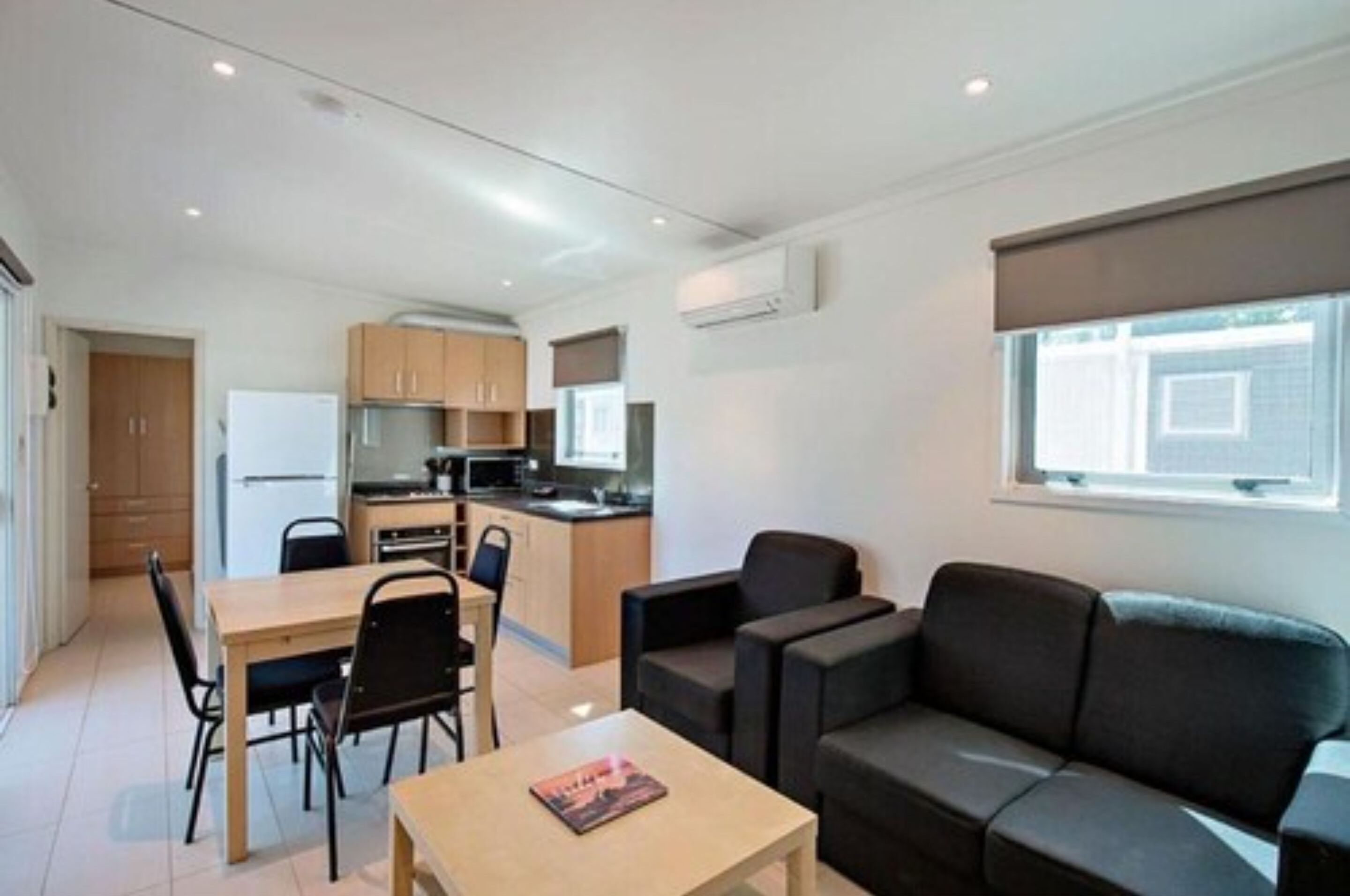 Un apartamento moderno y bien iluminado con comedor, cocina y sala de estar con sofá y mesa de centro.