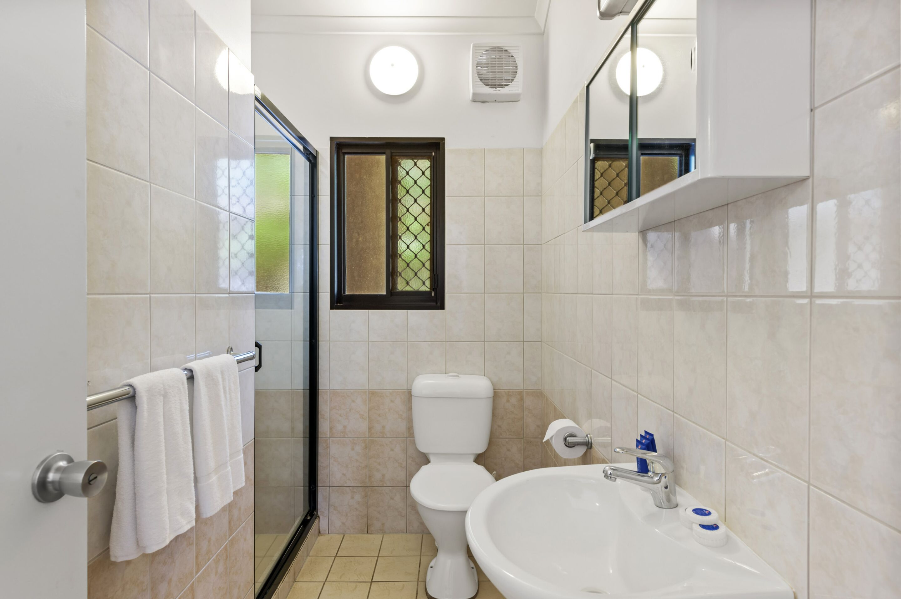 Un baño con inodoro, lavamanos y cabina de ducha de vidrio.