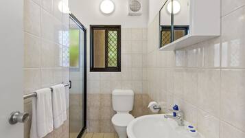 Un baño con inodoro, lavamanos y cabina de ducha de vidrio.