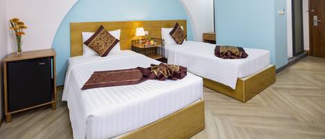 Habitación de hotel con dos camas, una mesita de noche, una lámpara y un armario pequeño.