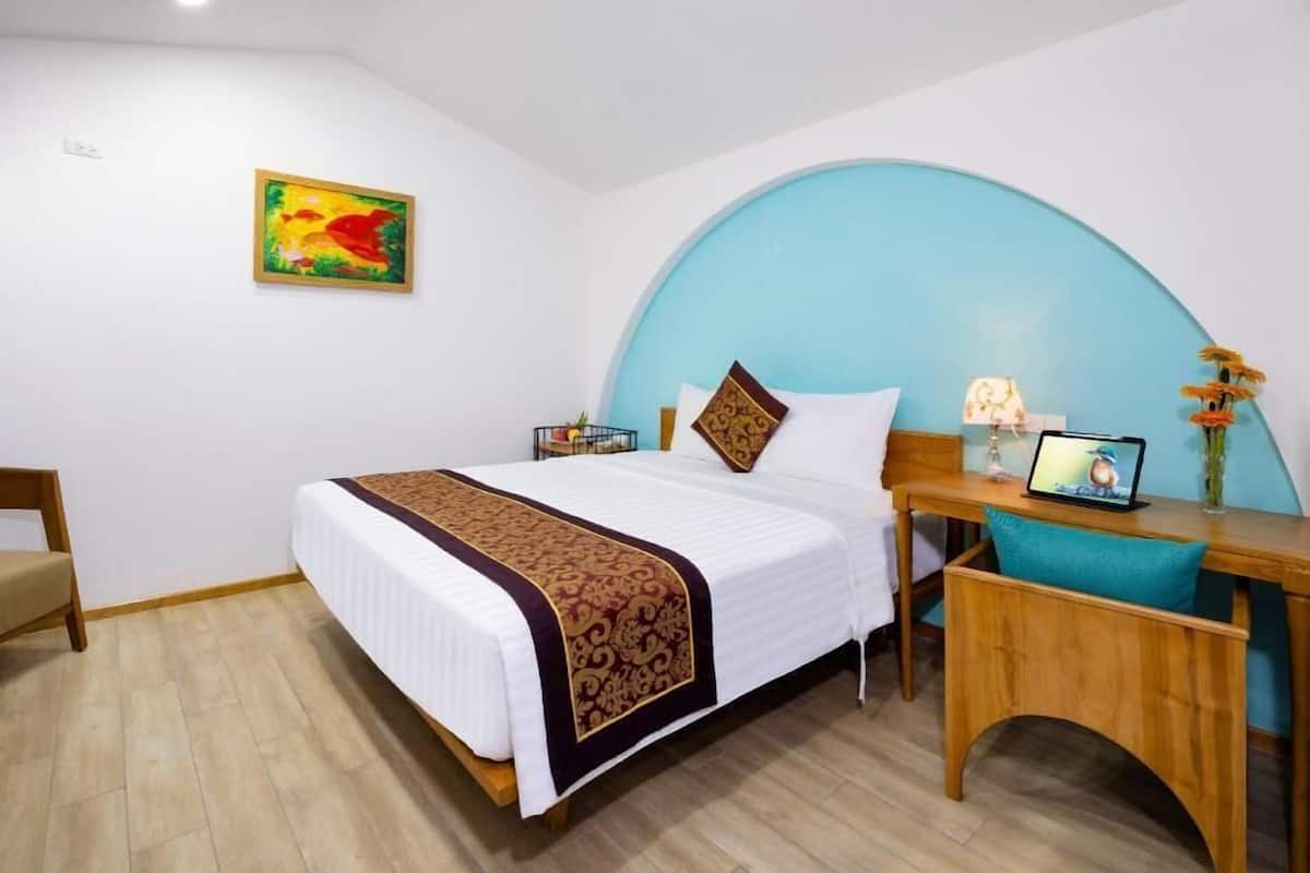 A hotel room with a bed, desk, chair, and a curved wall.