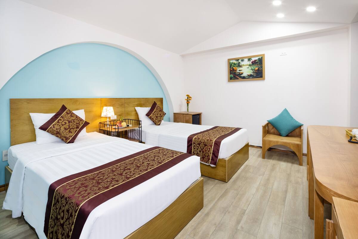 A hotel room with two beds, a desk, and a chair.