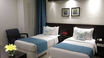 Habitación de hotel con dos camas, un escritorio, una silla y una mesita de noche con teléfono.